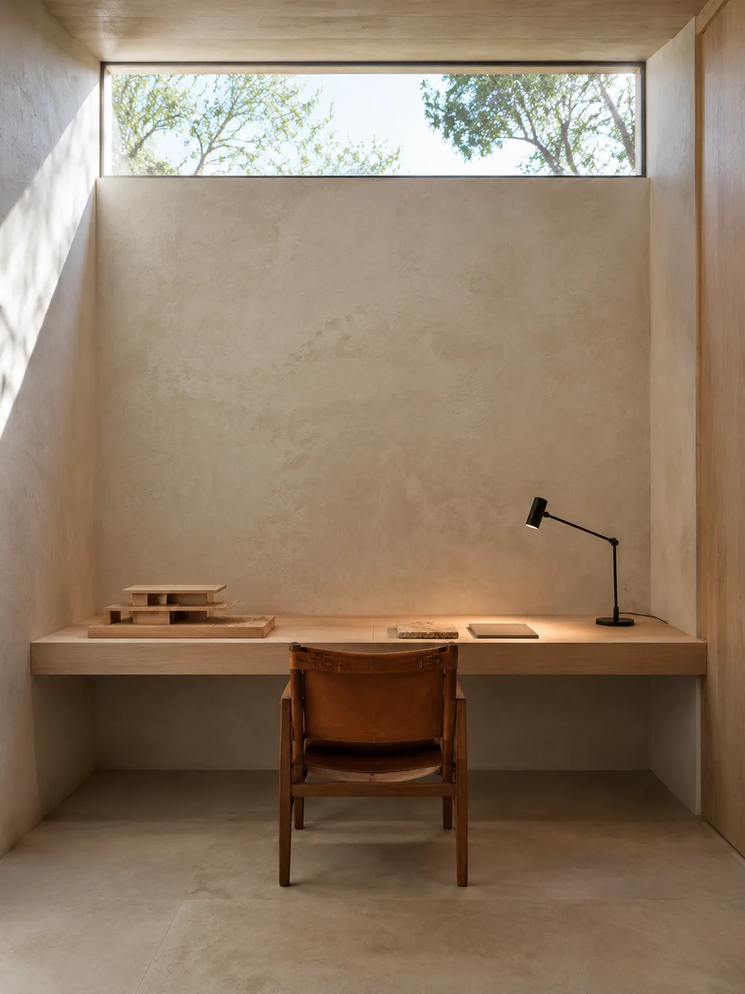 Minimalist architect's office with lime-plaster walls, a built-in pale-ash desk, one leather chair and a high clerestory window.